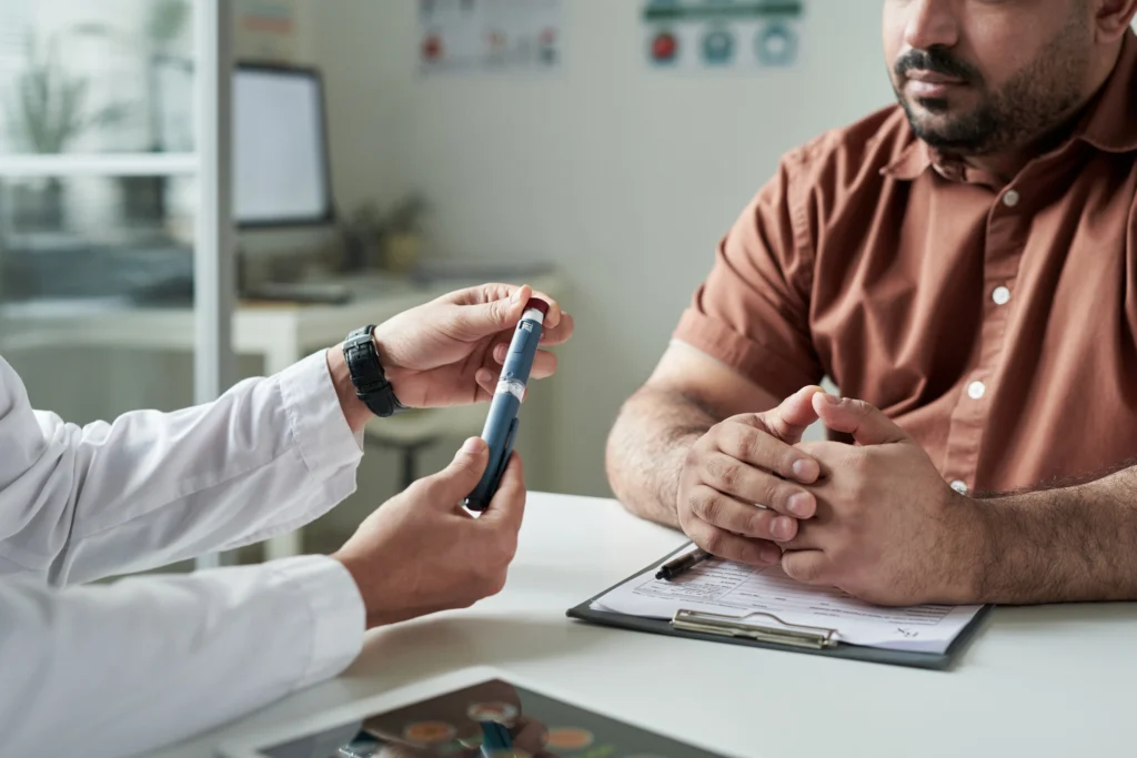 Image of a doctor and a patient in a consultation with no faces showing. Doctor holding a spring-loaded lancing device